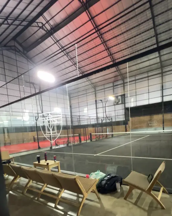 Dark court with the Padel Barn crest on the glass
